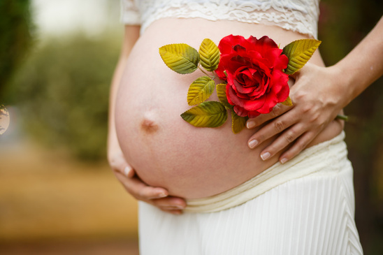 Pregnant Woman With Red Rose Flower on Her Belly